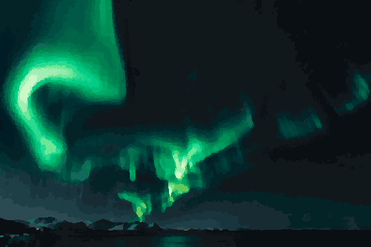 A breathtaking view of the aurora borealis brightly illuminating the night sky above a body of water, with hills in the background, pixel art