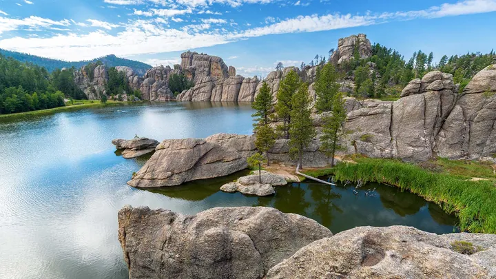 A stunning view of a lake surrounded by rocks and trees in the middle of a mountain range