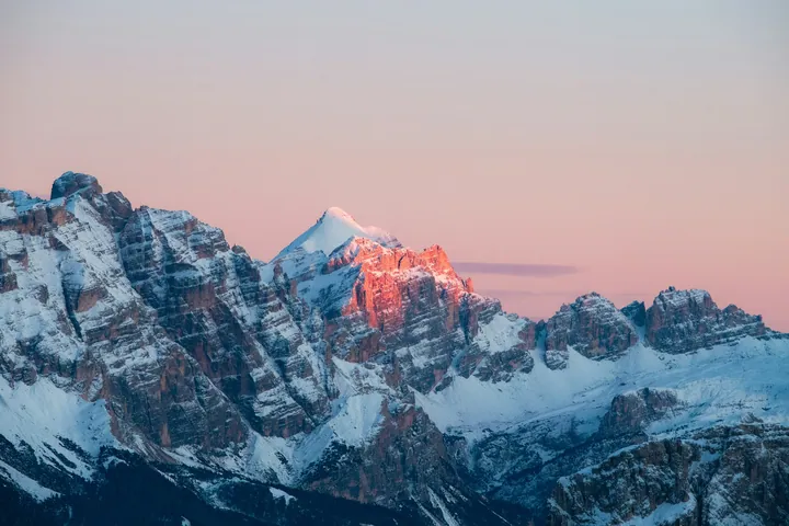 A majestic mountain range with snow-covered peaks in the background, illuminated by the setting sun