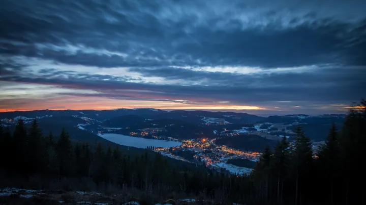 A breathtaking view from the top of a mountain at dusk, with the sun setting in the background