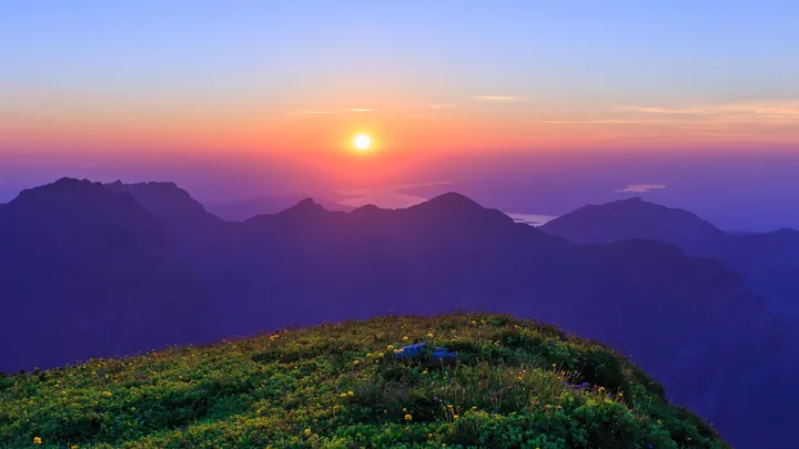 A breathtaking view of the sun setting over the mountains from the top of a mountain
