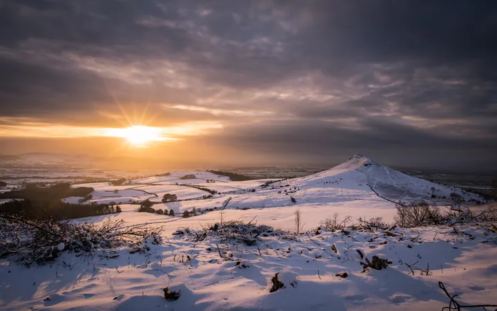 A beautiful winter sunset over a snowy field with a mountain in the background