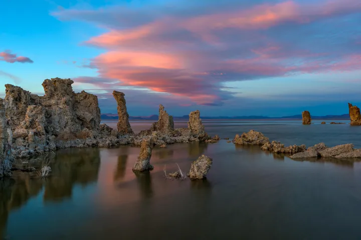 A stunning sunset at Mono Lake in California, with the water in the foreground and rocks in the middle