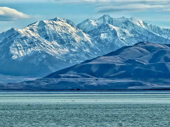 A large body of water with snow-capped mountains in the background