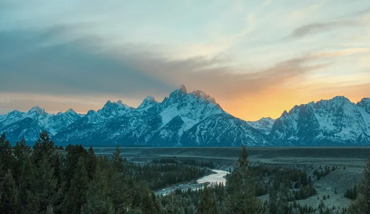 The majestic Grand Teton National Park in Wyoming, with its snow-capped mountains, lush trees, and winding river