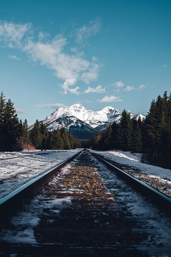 Snowy Railroad Tracks Winding Through Mountain Landscape wallpapers